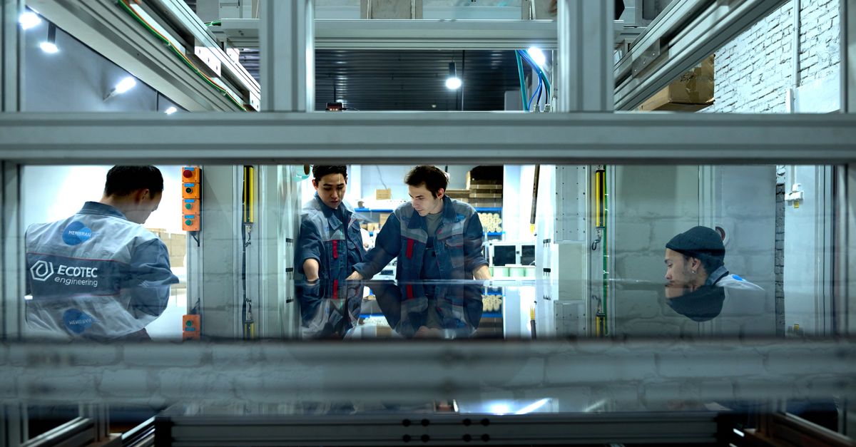 Engineers collaborating around equipment in a workshop setting.